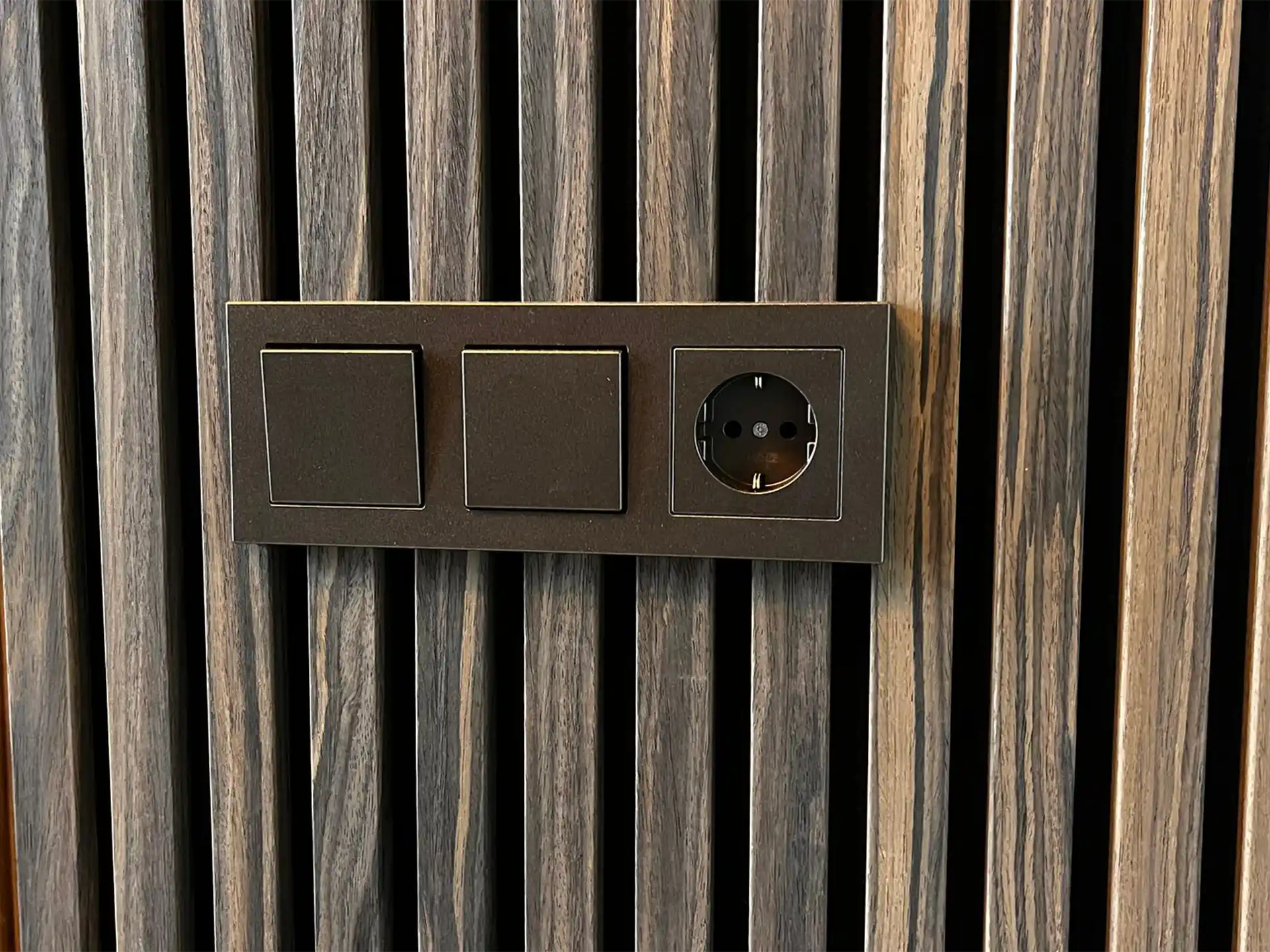 Detail van akoestische wandpanelen in gerookt eiken met geïntegreerd stopcontact