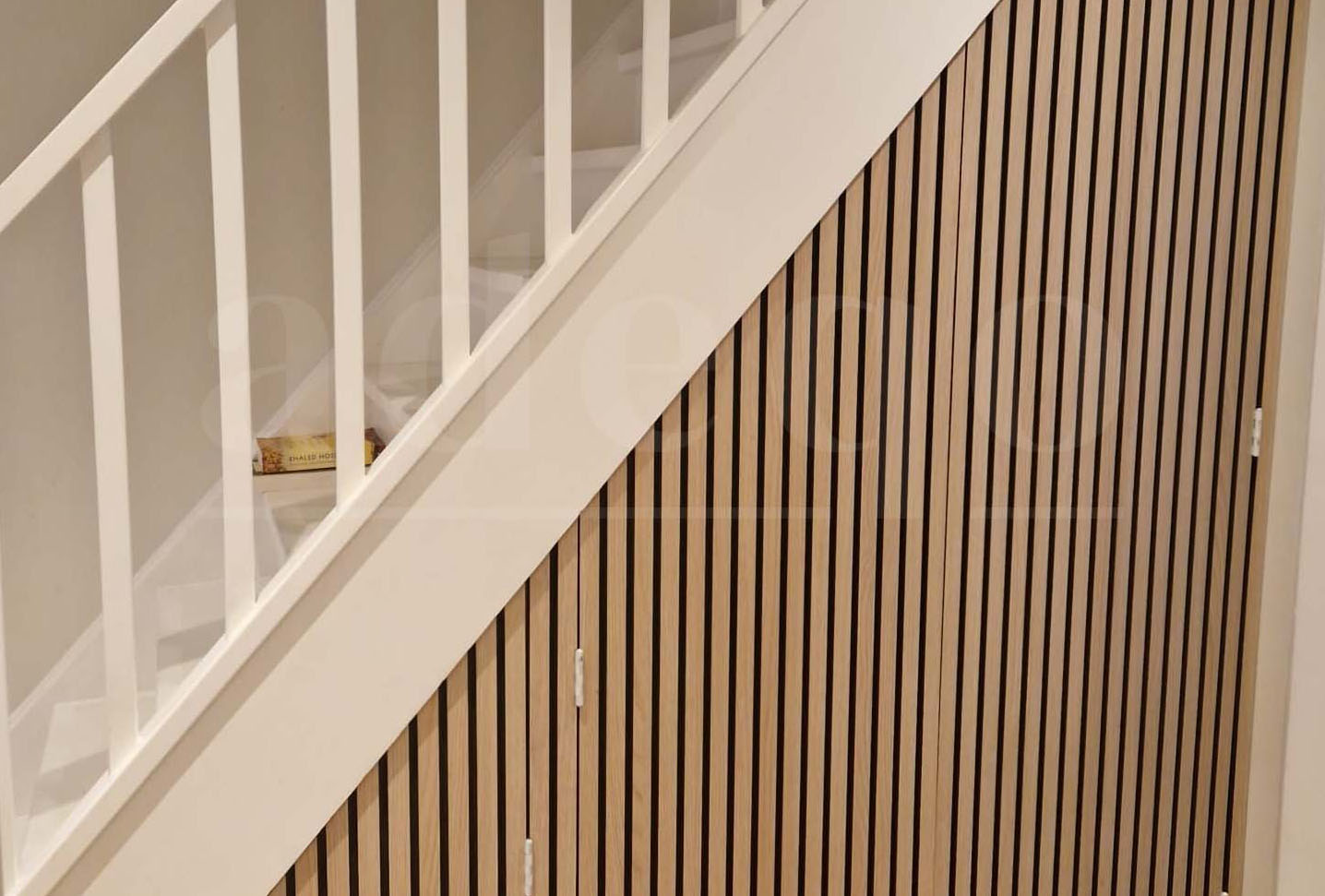 Inbouwkast bekleden met houten latjespanelen eiken fineer — trapkast in hal met schuine deur en ombouw bekleed met Adeqo wandpanelen