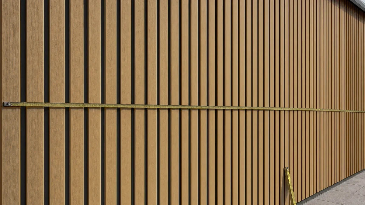 Stalen rolbandmaat gespannen over een teak composiet gevelwand om de breedte voor de gevelberekening op te meten