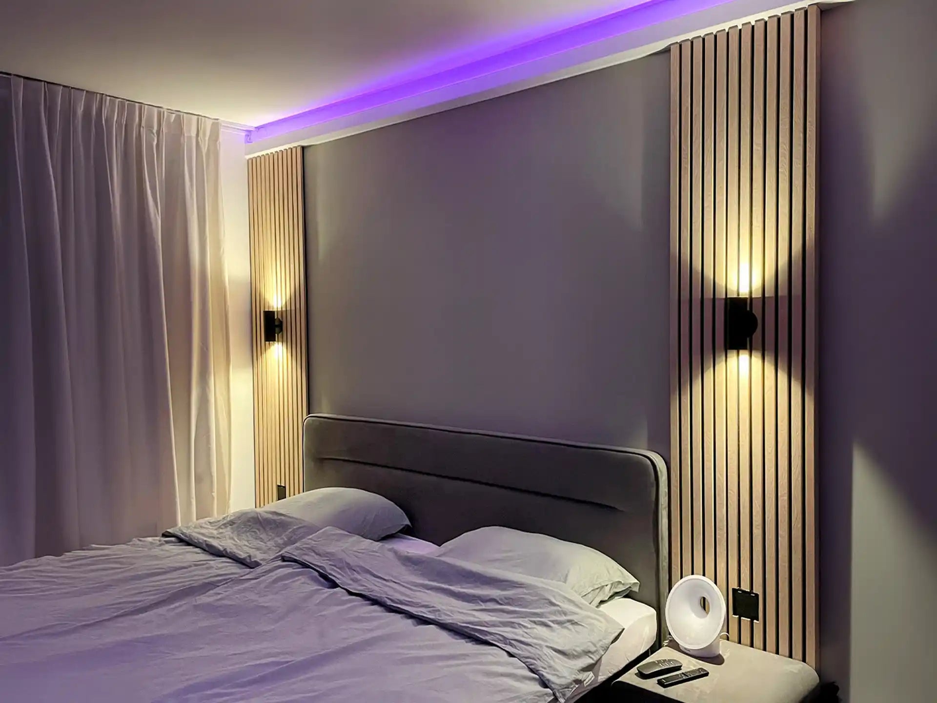 Akoestisch houten wandpaneel achter bed in moderne slaapkamer met sfeervolle verlichting