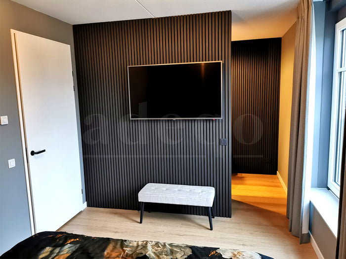 Slaapkamer met een TV-wand van akoestische wandpanelen in Zwart Eiken en een witte bank
