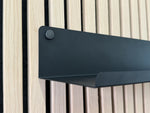 Detail van de zwarte wandplank met de handschroef waarmee hij op het akoestische wandpaneel vastzit