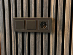 Detail van akoestische wandpanelen in gerookt eiken met geïntegreerd stopcontact