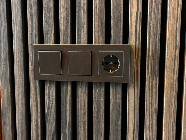 Detail van akoestische wandpanelen in gerookt eiken met geïntegreerd stopcontact