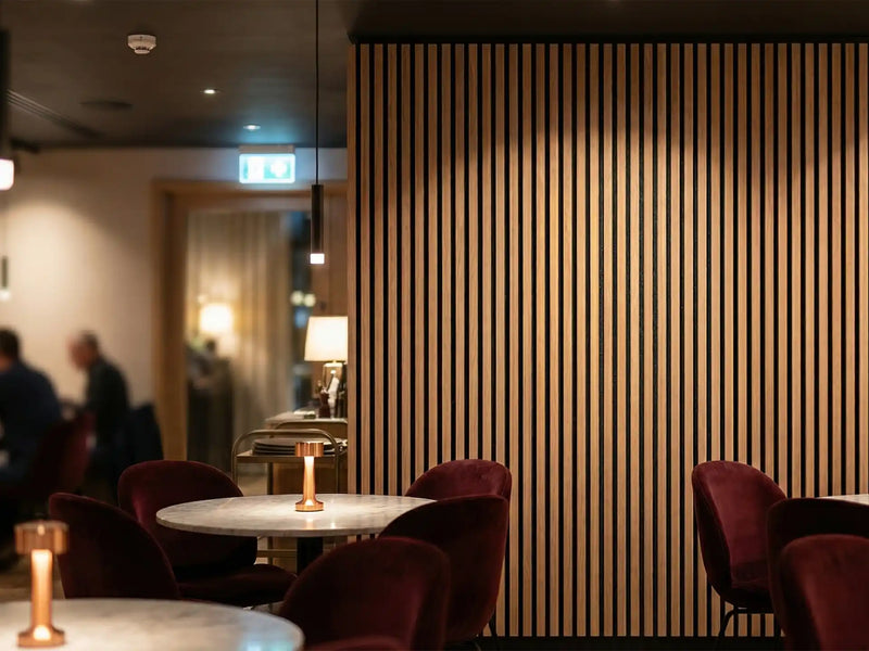 Restaurant met een wand van verticale houten akoestische wandpanelen achter de tafels