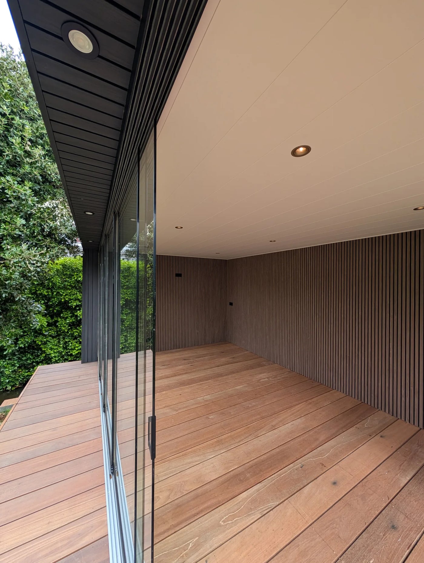 Tuinkamer gezien vanaf de vlonder, met houten lattenwand, licht plafond en inbouwspots